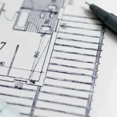 Rysunek techniczny z miarką i długopisem. Precyzja jest kluczowa, by uniknąć odpowiedzialności projektanta za błędy w projekcie.