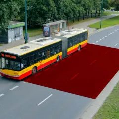 Czerwony obszar na drodze pokazuje bezpieczną odległość między samochodami w terenie zabudowanym, ilustrując przestrzeń dla autobusu.
