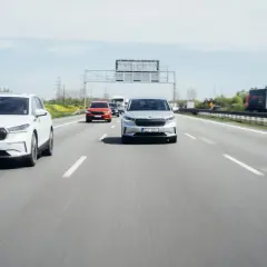 Na autostradzie biały i srebrny SUV jadą z zachowaniem bezpiecznej odległości między samochodami na światłach.