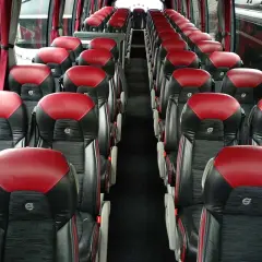Wnętrze autobusu z rzędami czerwono-czarnych siedzeń. Zastanawiasz się, ile może jechać kierowca, gdy wszyscy pasażerowie są już na swoich miejscach.