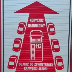 Grafika na drzwiach wozu strażackiego przedstawia korytarz życia, symbolizujący drogę dla pojazdów ratunkowych.
