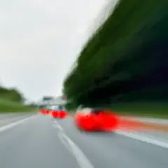 Dynamiczne wyprzedzanie z lewej strony na autostradzie. Czerwone światła samochodów zamazane przez ruch.