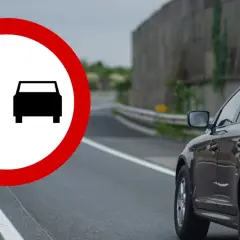 Znak zakazu wyprzedzania na drodze jednokierunkowej. Czarny SUV jedzie po drodze, gdzie wyprzedzanie jest zabronione.