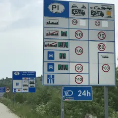 Znaki drogowe informujące o opłatach i dopuszczalnych predkosci na drodze. Widać ograniczenia dla samochodów, motocykli i pojazdów powyżej 3,5 tony.