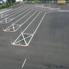 Plac manewrowy z pachołkami i białymi liniami, idealny do nauki, jak kręcić kierownicą podczas jazdy po łuku.