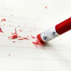 Czerwona gumka ołówka ściera ślady na kartce w linie. Co to za bałagan?