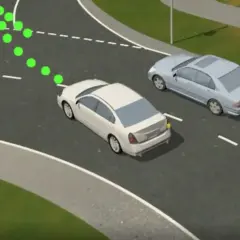 Zielone kropki wskazują prawidłowy zjazd z ronda na który pas. Dwa samochody na drodze.