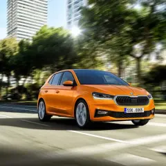 Pomarańczowa Skoda Fabia jedzie po mieście. Idealny samochód, by nauczyć się, co trzeba umieć na pierwszą jazdę.