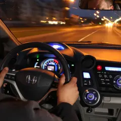 Kierowca prowadzi auto nocą. Czy w czasie jazdy w nocy masz obowiązek zwiększyć uwagę? Widok z wnętrza pojazdu na drogę i deski rozdzielcze.