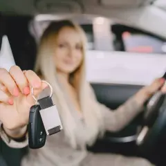 Kobieta z kluczykami do samochodu w dłoni, gotowa do jazdy. Czas na pierwsze samodzielne kilometry po zdaniu prawa jazdy!