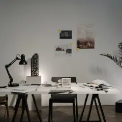 Biuro architektoniczne z modelem budynku, lampą, krzesłem i dokumentacją. Karta nadzoru autorskiego czeka na zatwierdzenie.
