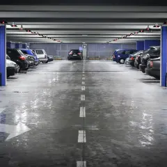 Wielopoziomowy plac postojowy, gdzie mokra podłoga parkingu odbija światła.