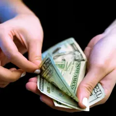 Dłonie liczą banknoty dwudziestodolarowe. Może to być związane z rozwiązaniem umowy o roboty budowlane za porozumieniem stron wzór.