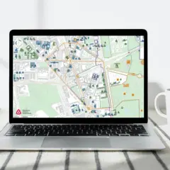 Mapa na ekranie laptopa pokazuje obszar wpisany do rejestru zabytków, z zaznaczonymi budynkami i ulicami.