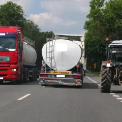 Czerwona ciężarówka próbuje wyprzedzanie na trzeciego, omijając traktor i inną cysternę na wąskiej drodze.