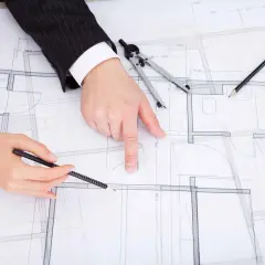 Rysunek techniczny, plan budynku, dyskusja nad projektem zgodnym z art. 36a prawo budowlane. Dłonie wskazują na szczegóły.
