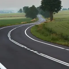 Droga wijąca się przez pola. Podwójna ciągła linia wyznacza pasy ruchu, przypominając, kiedy można przekroczyć podwójną ciągłą.