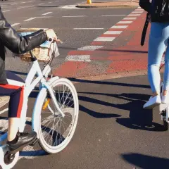Osoba na rowerze i osoba na hulajnodze elektrycznej jadą po ścieżce rowerowej.