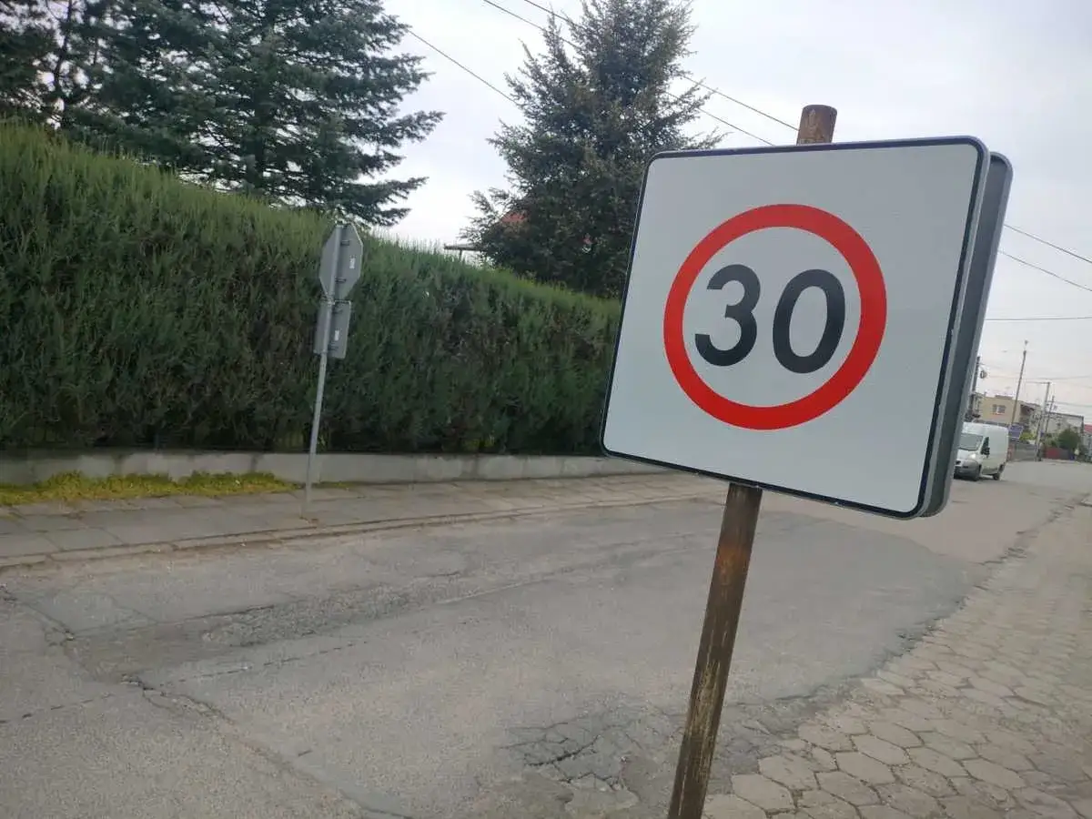 Znak ograniczenia prędkości do 30 km/h na drodze. Uważaj na te predkosci na drodze, zwłaszcza w pobliżu żywopłotu i chodnika.