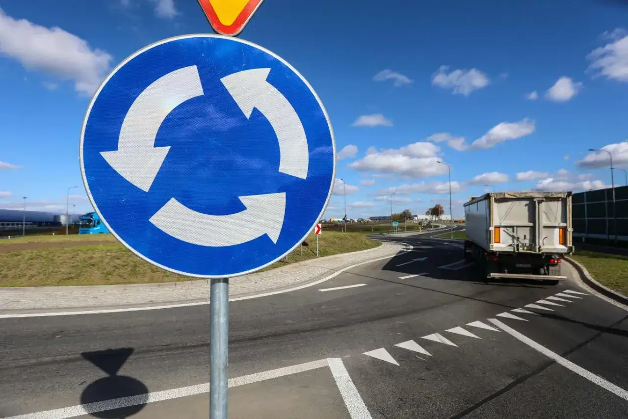 Znak ronda i droga z wyznaczonymi pasami ruchu. Ciężarówka wjeżdża na zjazd z ronda na który pas.