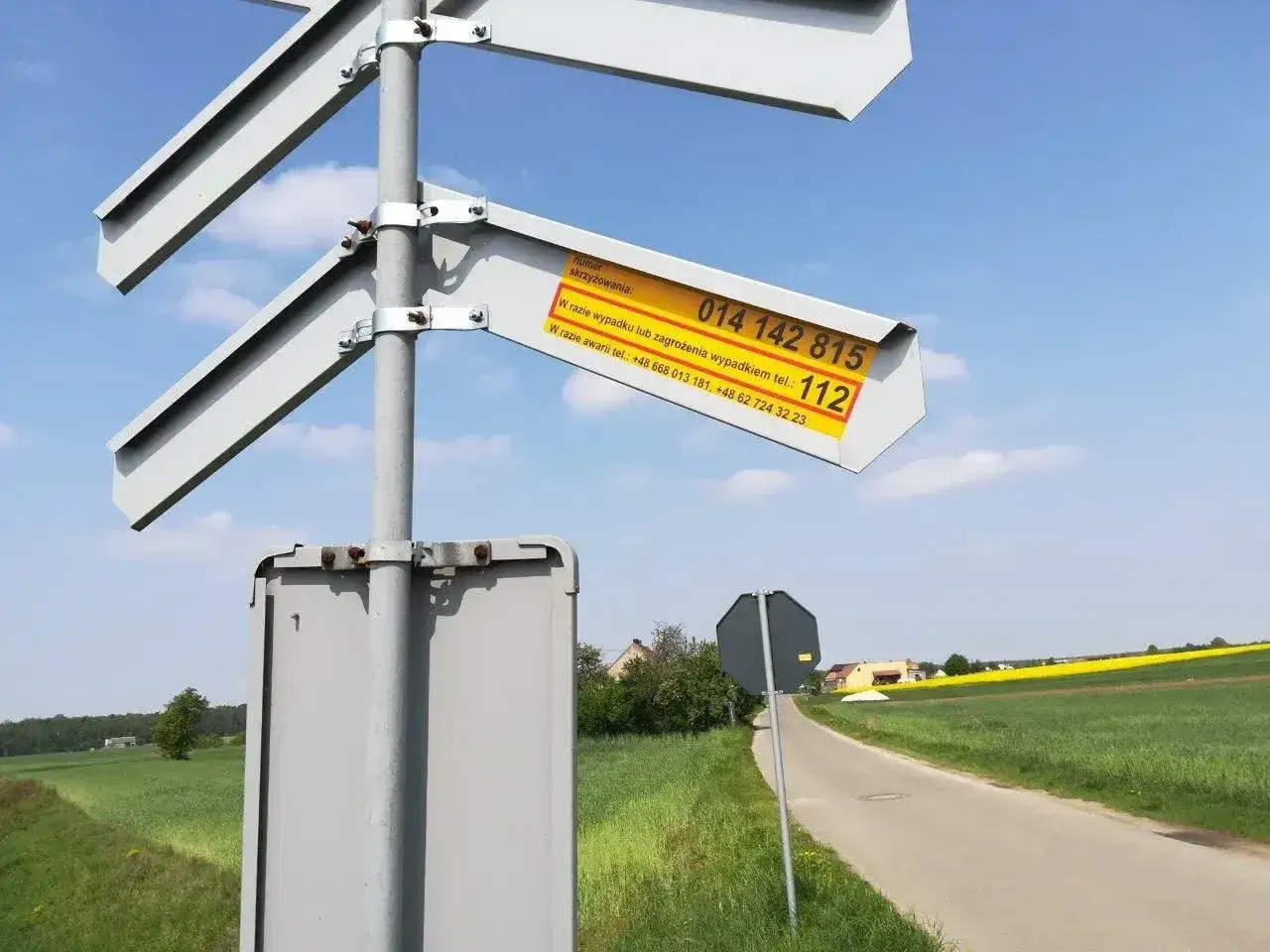 Znak drogowy z numerem skrzyżowania i numerami alarmowymi. W razie wypadku lub zagrożenia, kiedy należy zachować szczególną ostrożność, dzwoń pod 112.